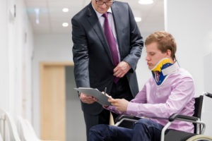 lawyer helping a wheelchair-bound patient fill out paperwork