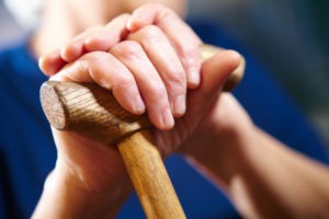 older man’s hands holding a cane