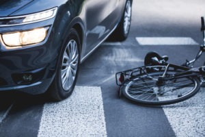 car next to a fallen bicycle in an intersection