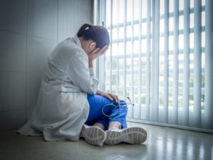 distressed female doctor sitting on the floor