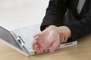 woman massaging her wrist at a keyboard
