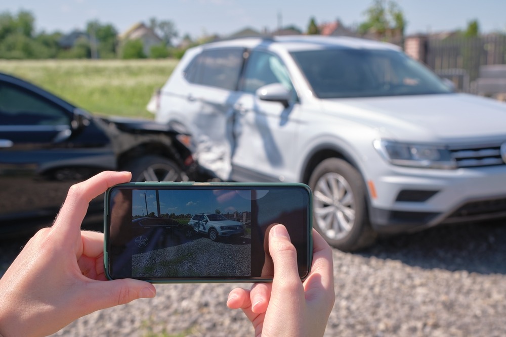 Stressed,Driver,Taking,Picture,On,Sellphone,Camera,Of,Smashed,Vehicle